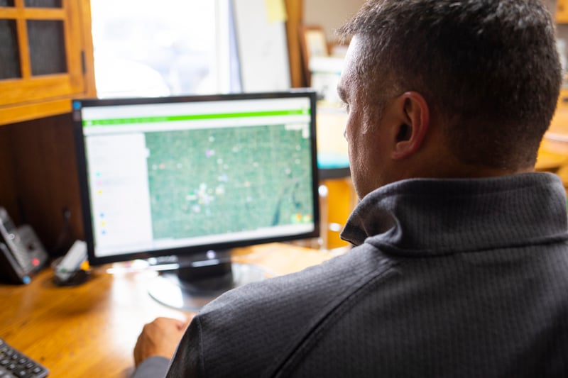 A man looking at the Agworld web app on a computer screen