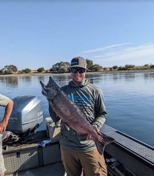 Justin Pearson holding up a large King Salmon catch on a boat